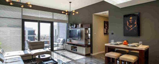 Modern living room apartment with large glass balcony doors, contemporary furniture, stylish lighting fixtures, and marble flooring, featuring a cozy and elegant interior design.