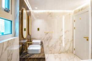 Luxurious marble bathroom with double vessel sinks, gold fixtures, and elegant mirrors, featuring modern design and high-end finishes for a sophisticated and stylish space.