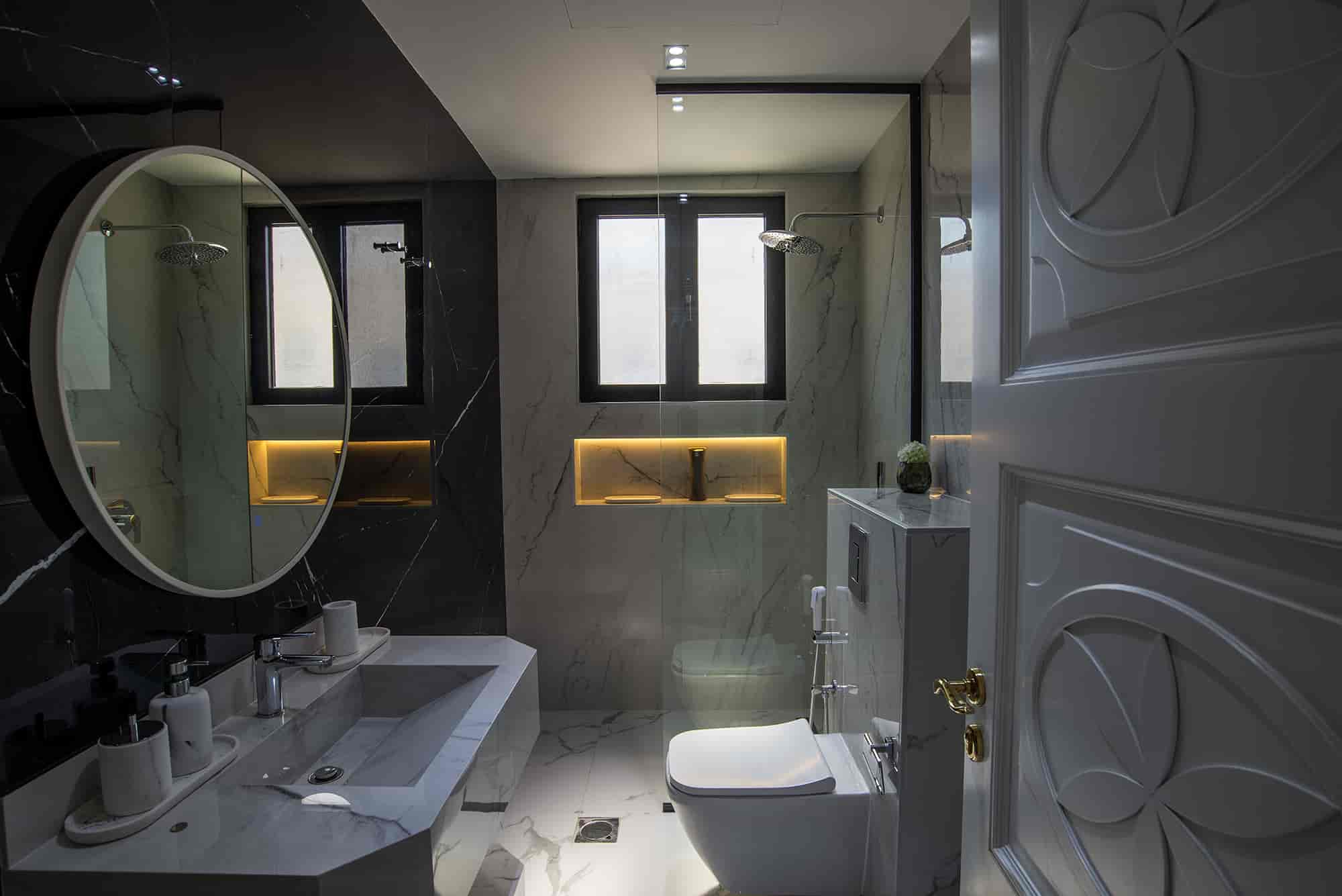 Polished marble bathroom with modern fixtures, dual showers, illuminated niche, and elegant decor, showcasing luxurious design and sleek black accents for sophisticated interior styling.